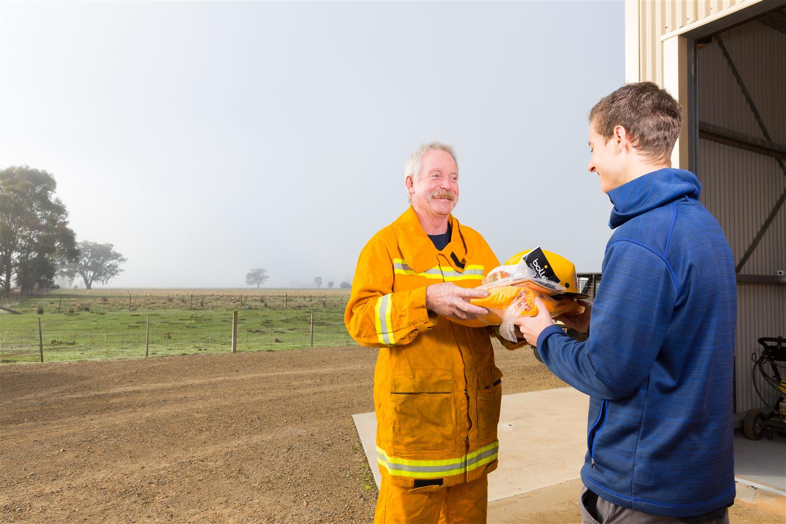 A uniformed member hands new turn out gear to a new member
